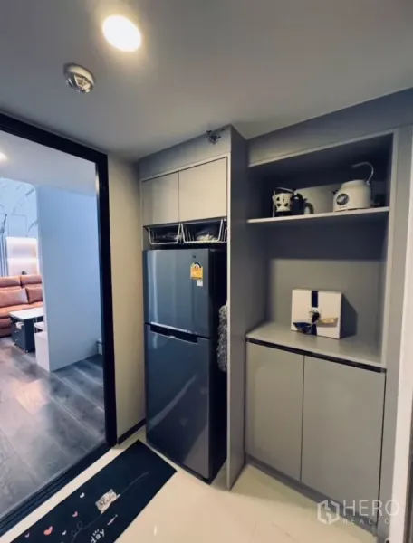 Condominium for rent in Chatuchak, Bangkok - Compact pantry with tall fridge and built-in cabinets next to the living area.