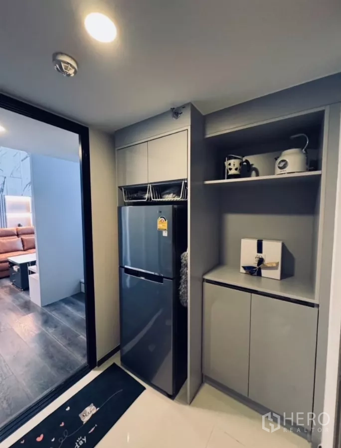 Condominium for rent in Chatuchak, Bangkok - Compact pantry with tall fridge and built-in cabinets next to the living area.