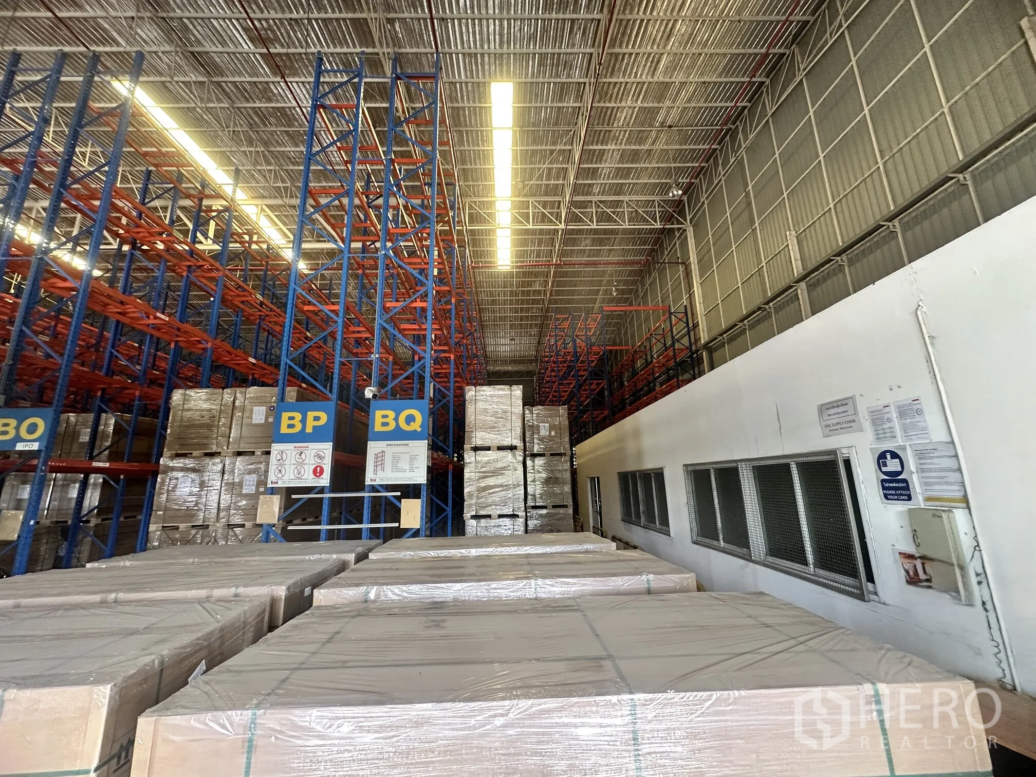 Warehouse for rent in Lat Krabang, Bangkok - Interior of warehouse with tall pallet racking, stacked pallets, and side windows.