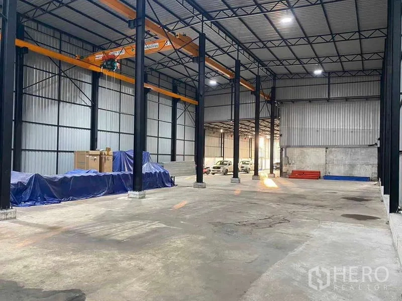 Warehouse for sale in Mueang Samut Prakan, Samut Prakan - Open warehouse floor with steel columns, crane rails and parking area at the rear.
