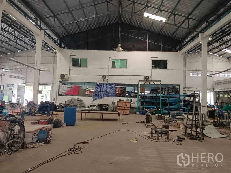Warehouse for rent or sale in Nong Suea, Pathum Thani - Front wall with mezzanine offices and storage racks inside the warehouse.