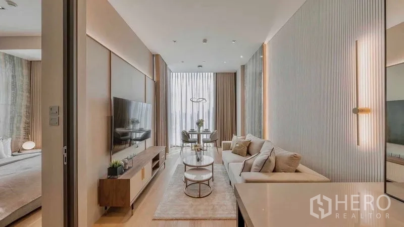 Condominium for rent or sale in Pathum Wan, Bangkok - Long living space with sofa, media console and dining nook at full-height windows.