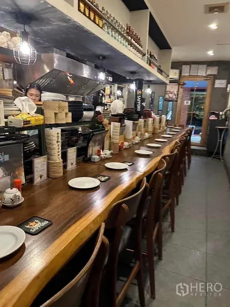 อาคารพาณิชย์ ให้เช่าหรือขายในWatthana, Bangkok - เคาน์เตอร์ไม้ยาวพร้อมเก้าอี้เรียงเป็นระเบียบและชุดจานชามต่อเนื่องถึงทางเข้า