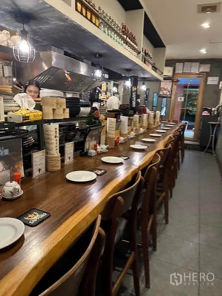 อาคารพาณิชย์ ให้เช่าหรือขายในWatthana, Bangkok - เคาน์เตอร์ไม้ยาวพร้อมเก้าอี้เรียงเป็นระเบียบและชุดจานชามต่อเนื่องถึงทางเข้า