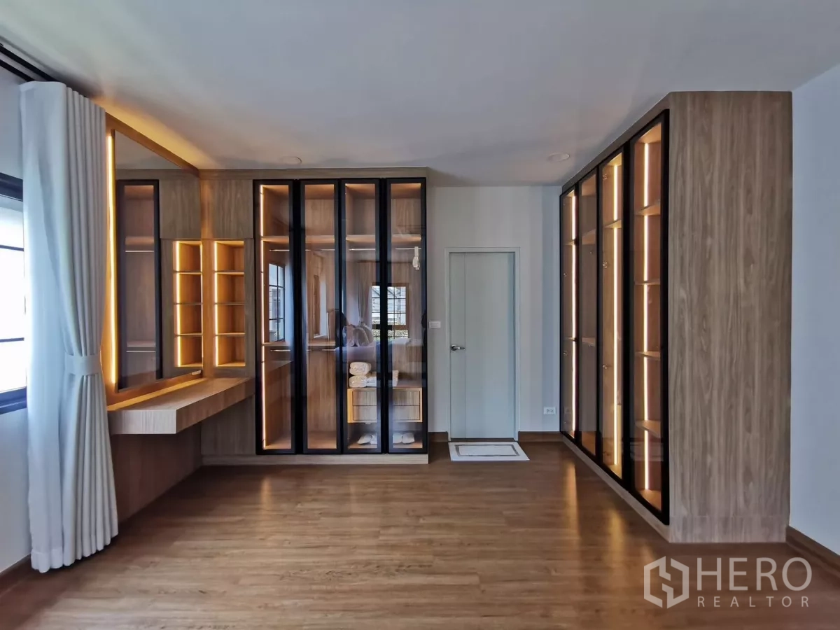 Detached House for rent in Bang Phli, Samut Prakan - Built-in walk-in wardrobe with glass-front cabinets and illuminated dressing table.