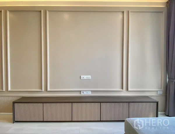 คอนโด ขายในPathum Wan, Bangkok - ผนังทีวีตกแต่งบัว พร้อมตู้เก็บของยาวและช่องปลั๊กไฟ