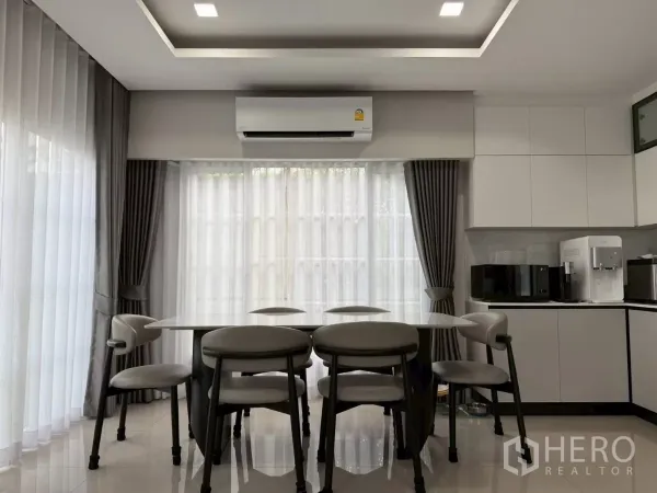 Detached House for rent in Bang Phli, Samut Prakan - Dining area for six beside tall windows, linked to modern built-in kitchenette and AC.
