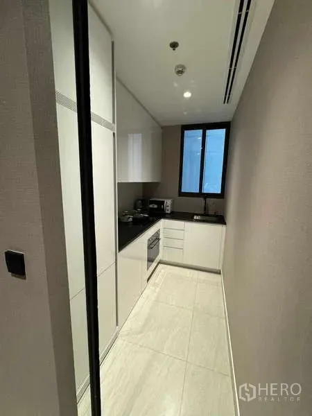 公寓 出租在Bang Rak, Bangkok - 一字型封闭厨房，白色橱柜、黑色台面与窗户