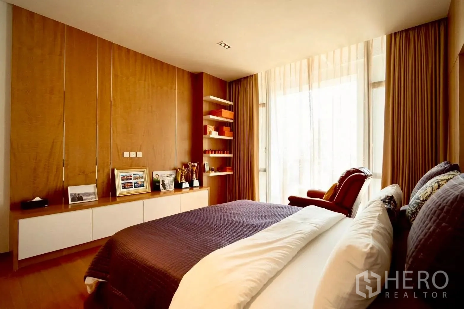 Condominium for sale in Sathon, Bangkok - Bright bedroom with large window, shelves, and warm wood floors.