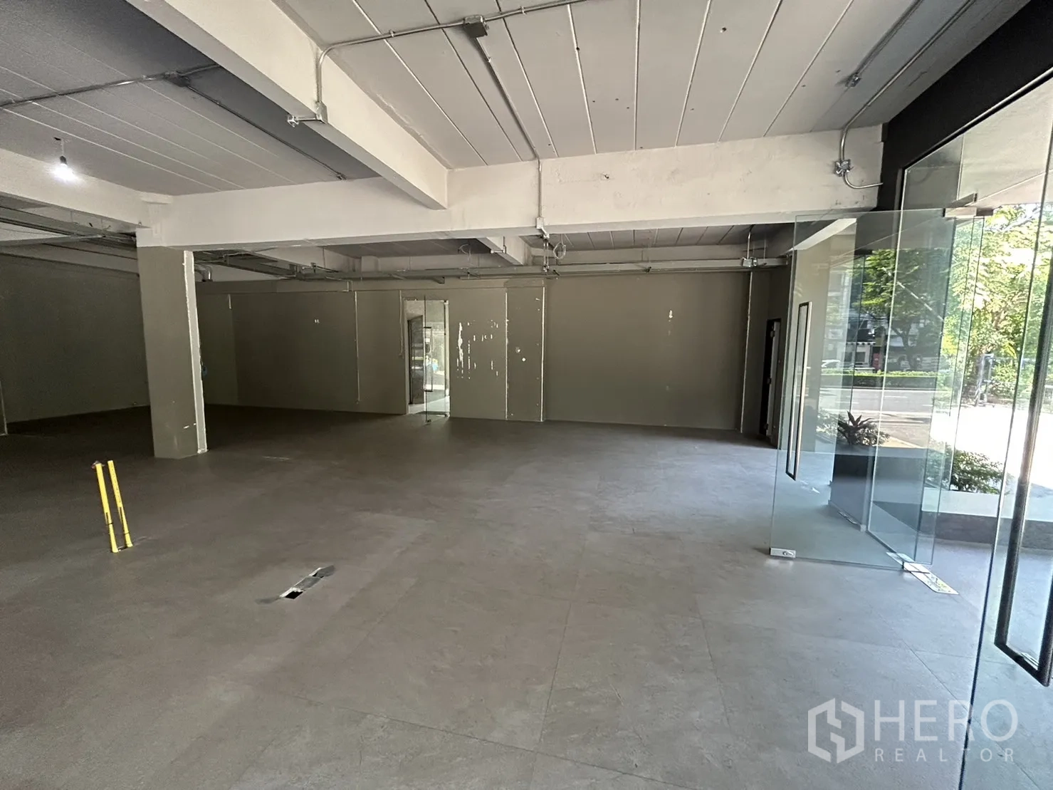 零售空间 出租在Suan Luang, Bangkok - 展厅内部朝向玻璃隔断房与后部服务门。