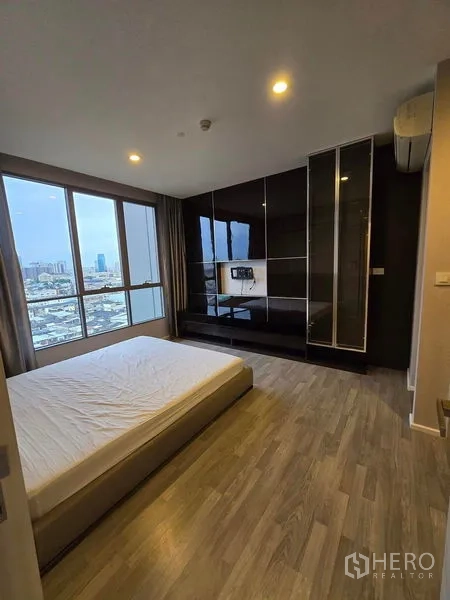 Condominium for rent - Primary bedroom with large windows, glossy built-in wardrobe and city skyline view.