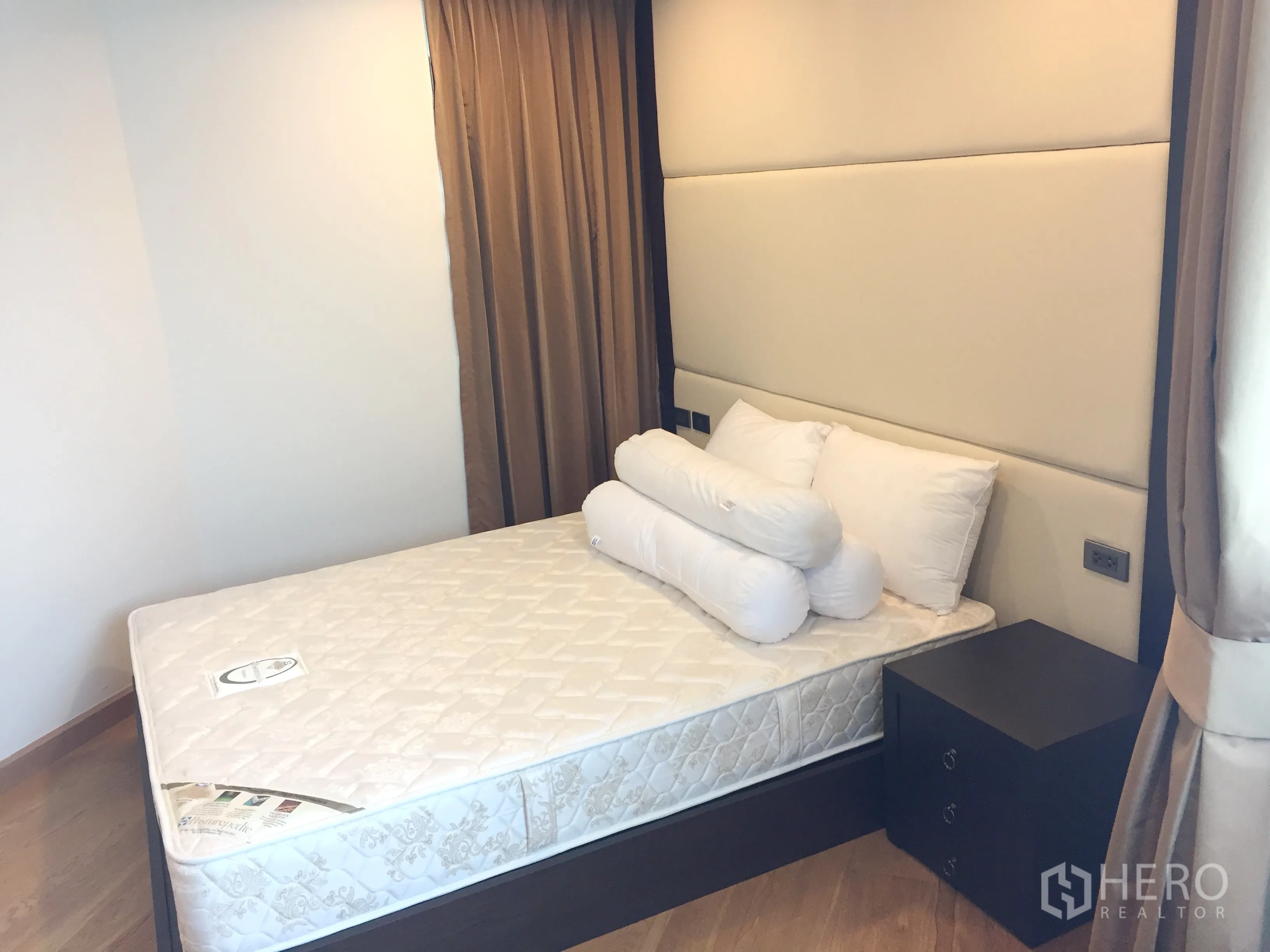 Condominium for rent in Sathon, Bangkok - Cozy bedroom with padded headboard, bedside table and thick blackout curtains.