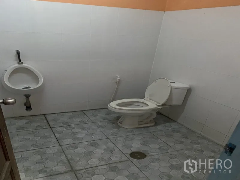 货栈 出租在Bueng Kum, Bangkok - 仓库内卫生间，配有坐便器和小便池，瓷砖地面，整洁明亮。