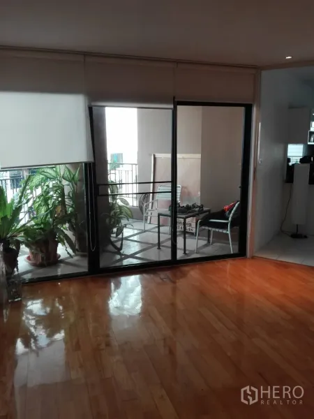 คอนโด ให้เช่าในKhlong Toei, Bangkok - ประตูกระจกบานเลื่อนเปิดสู่ระเบียงในร่ม มีต้นไม้กระถางและชุดโต๊ะเก้าอี้กลางแจ้ง