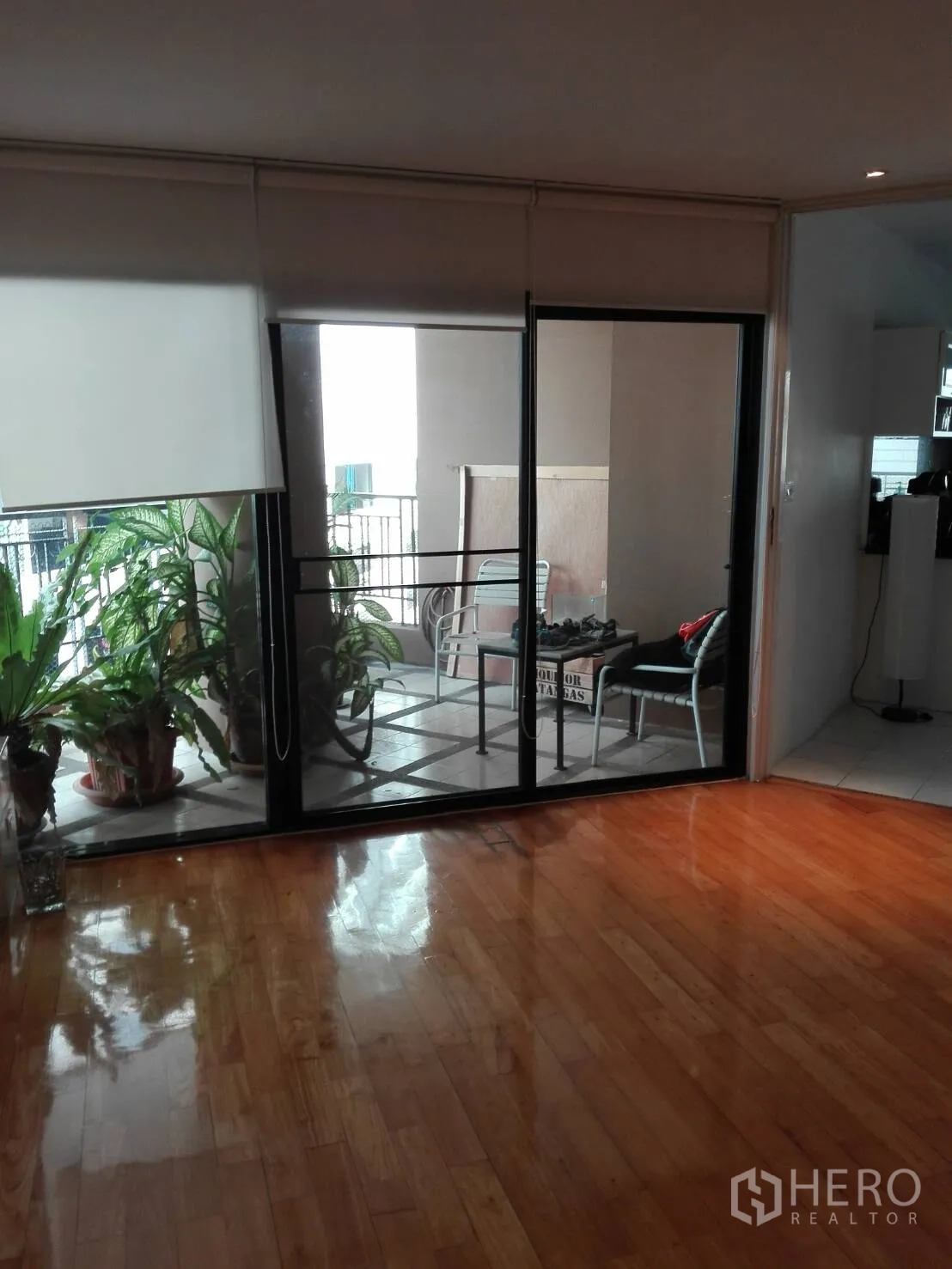 คอนโด ให้เช่าในKhlong Toei, Bangkok - ประตูกระจกบานเลื่อนเปิดสู่ระเบียงในร่ม มีต้นไม้กระถางและชุดโต๊ะเก้าอี้กลางแจ้ง