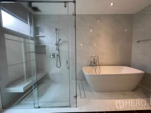 Detached House for rent in Bang Khen, Bangkok - Luxury bathroom featuring a frameless glass shower with bench and a freestanding bathtub.
