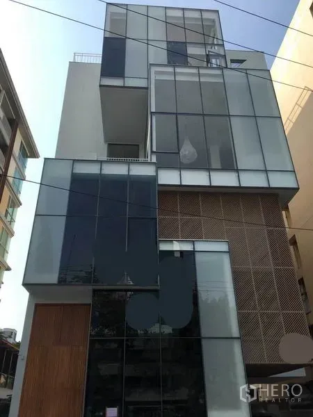 带办公室的家 出租在Phaya Thai, Bangkok - 街景视角的玻璃与木饰面家用办公楼外立面，方盒体量，位于曼谷帕亚泰。