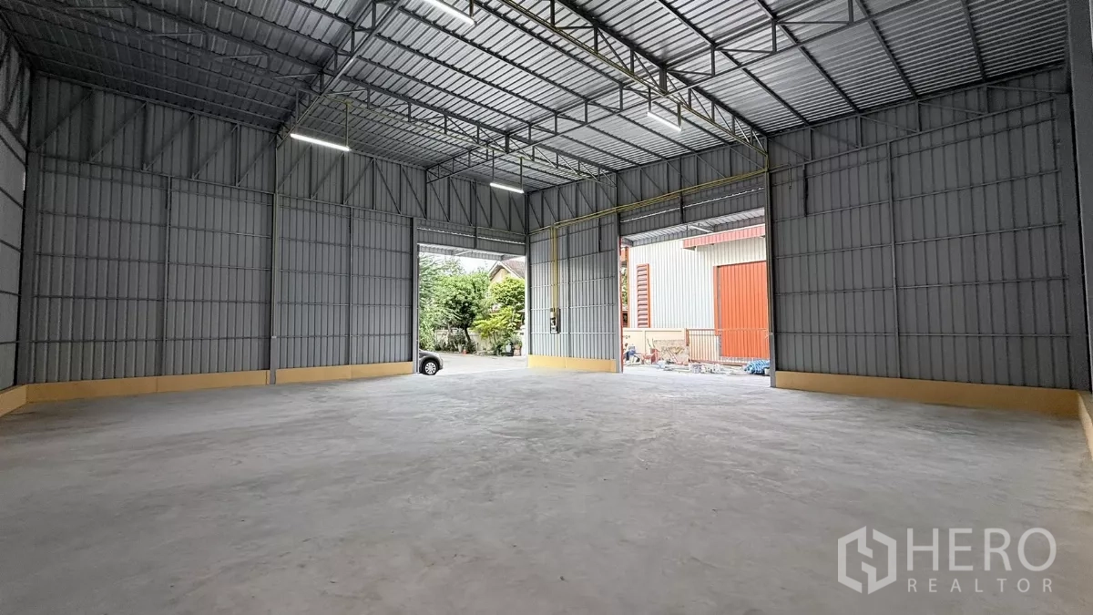 Warehouse for rent in Wang Thonglang, Bangkok - Spacious warehouse interior with tall steel truss roof and smooth concrete floor.