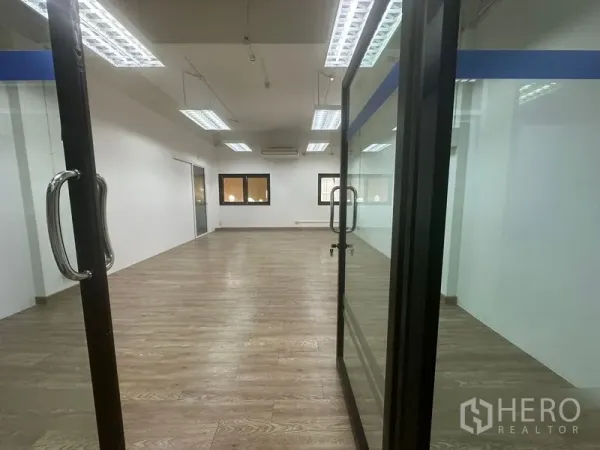 办公空间 出租在Chatuchak, Bangkok - 不锈钢把手玻璃入口，通向开放式办公室，设空调与木地板。