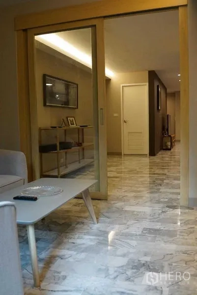 公寓 出租在Watthana, Bangkok - 大理石地面的走廊，通过木质推拉门通向小客厅。