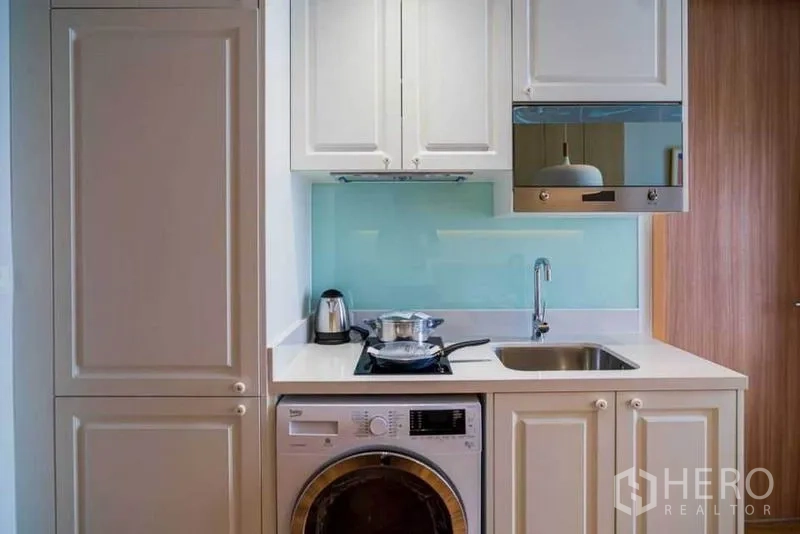 คอนโด ให้เช่าในWatthana, Bangkok - ครัวขนาดกะทัดรัด ตู้สีขาว เตาและซิงก์ เครื่องดูดควัน กระจกกันเปื้อน และเครื่องซักผ้า