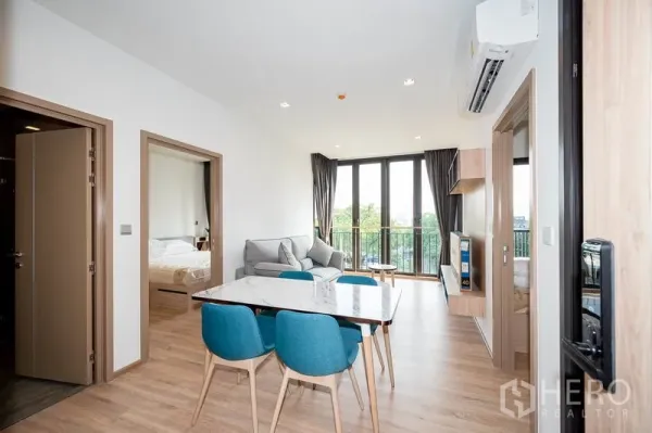 คอนโด ให้เช่าในWatthana, Bangkok - พื้นที่นั่งเล่นและรับประทานอาหารสว่างโปร่ง โต๊ะหินอ่อน เก้าอี้สีน้ำเงิน โซฟา และหน้าต่างเต็มบานเปิดสู่ระเบียง