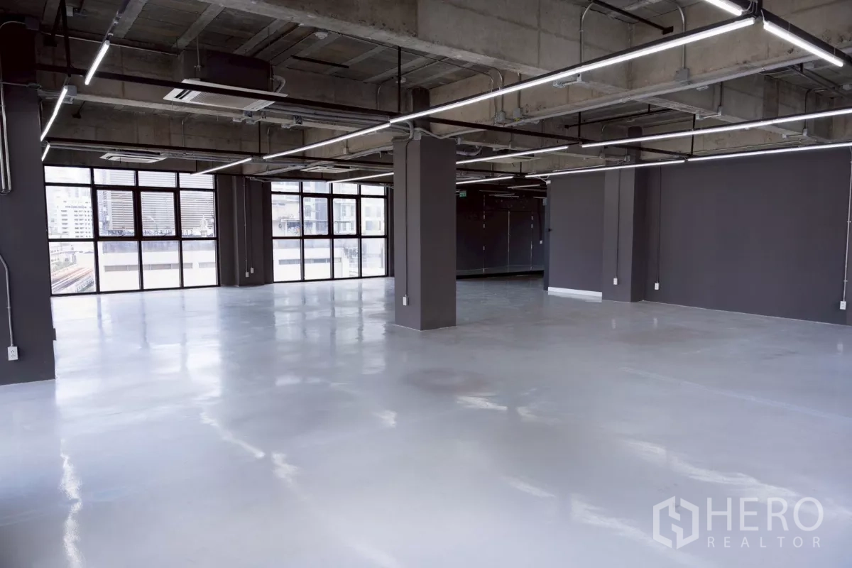 Office Space for rent - Open office floor with structural columns, glossy concrete floor and grid LED lighting.