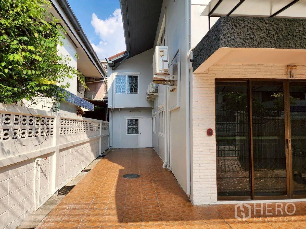 บ้านเดี่ยว for rent in Huai Khwang, Bangkok - ด้านข้างบ้านภายนอก พื้นกระเบื้องทางเดินติดกำแพงสีขาว