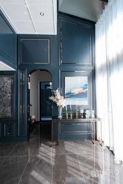 独立式住宅 出售在Prawet, Bangkok - 入口大厅，蓝色墙板、拱形门洞与陈列桌及纱帘。