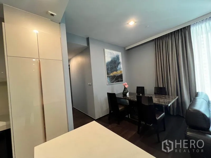 Condominium for rent in Watthana, Bangkok - Dining area with four-seat marble table beside a large curtained window.