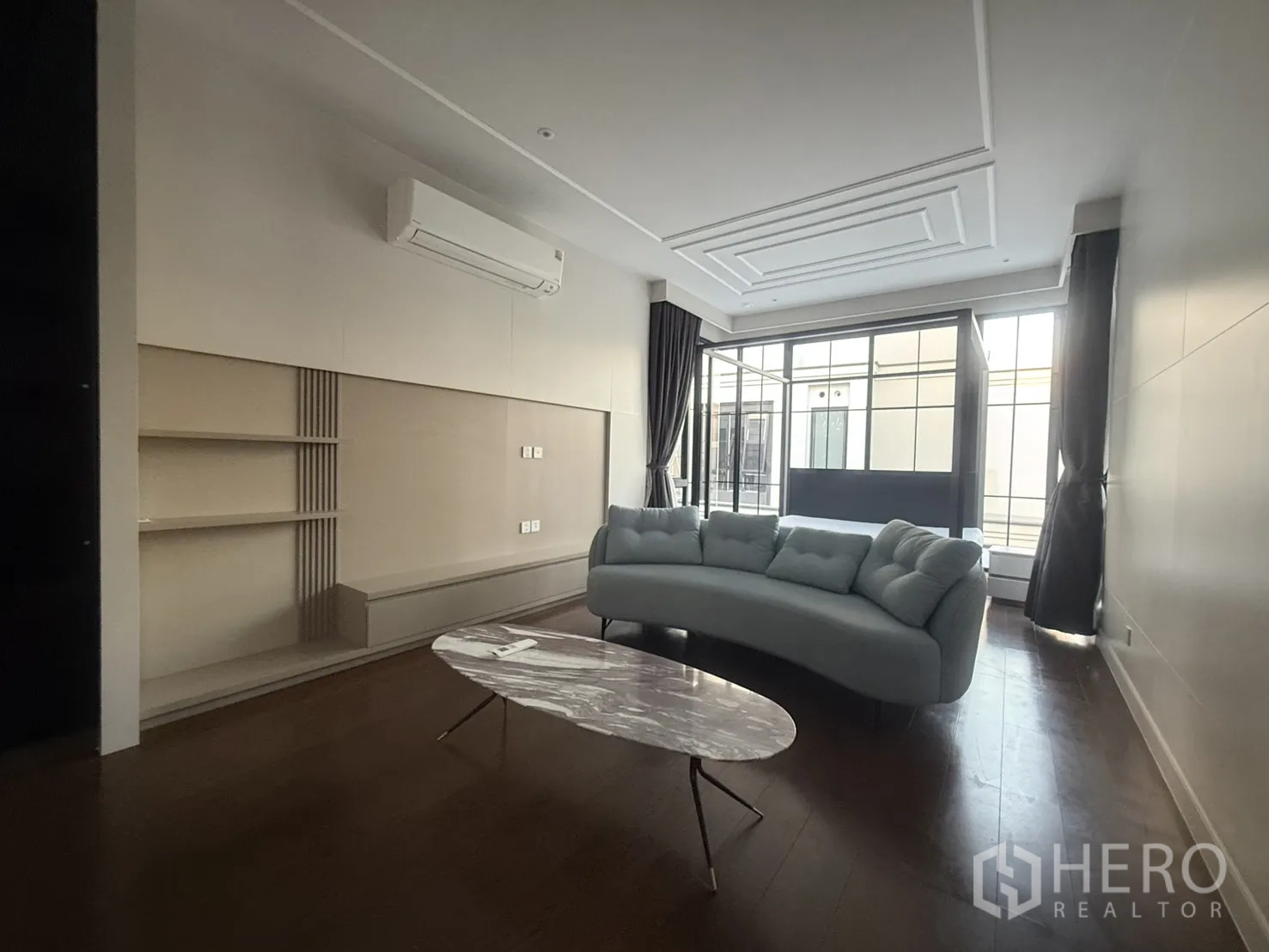 Detached House for rent in Saphan Sung, Bangkok - Living area with curved sofa, marble coffee table and tall windows.