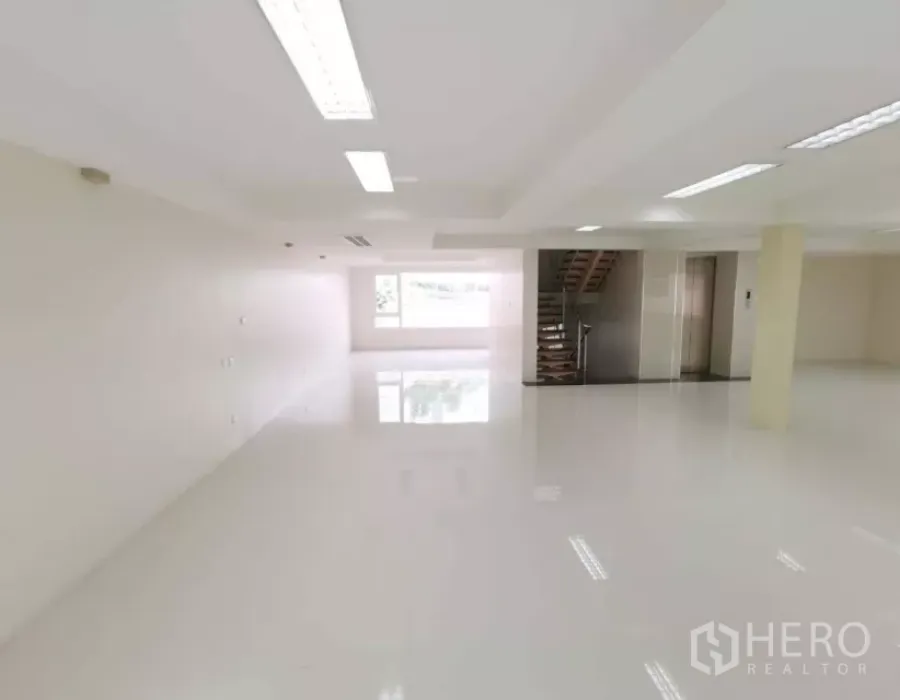 独立商业地产 出售在Bang Rak, Bangkok - 明亮的开放式楼层，白色地面、嵌入式照明，带窗户、内部楼梯与电梯前厅。