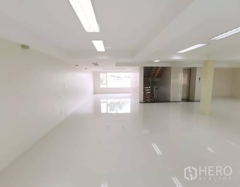 独立商业地产 出售在Bang Rak, Bangkok - 明亮的开放式楼层，白色地面、嵌入式照明，带窗户、内部楼梯与电梯前厅。