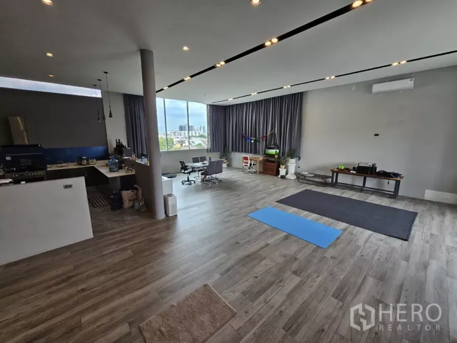 สำนักงาน ให้เช่า - พื้นที่สำนักงานแบบเปิด ปูพื้นลามิเนตไม้ มีแพนทรี ไฟแขวน และหน้าต่างบานกว้างมองเห็นวิวเมือง.
