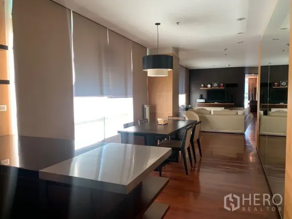 Condominium for rent - Open-plan dining and kitchen area with pendant light, long windows with roller blinds, and polished wooden flooring.