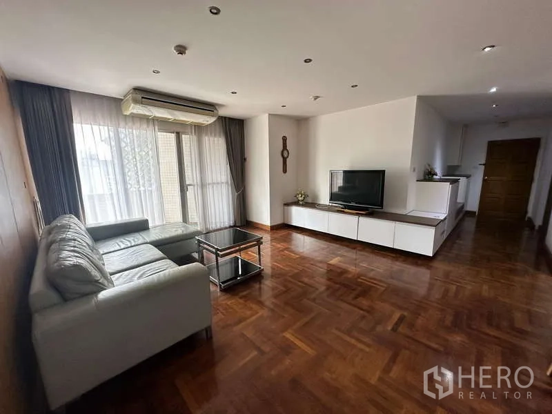 คอนโด ให้เช่าในWatthana, Bangkok - ห้องรับแขกแบบโอเพนสเปซ โซฟา L-Shape ชั้นวางทีวี และผ้าม่านสูงจรดเพดาน