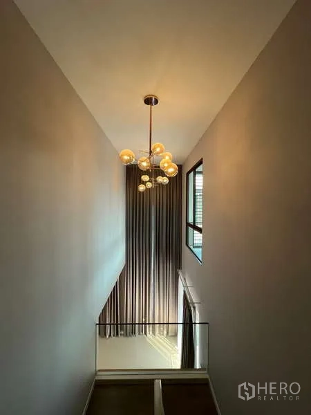 บ้าน ให้เช่าในBang Kapi, Bangkok - โถงบันไดเพดานสูง มีผ้าม่านทิ้งยาวและโคมไฟโมเดิร์น