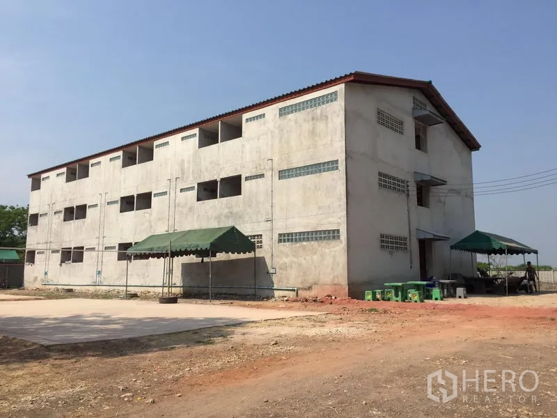 Factory for rent or sale in Samut Sakhon - Three-storey staff dormitory building with canopies next to the factory complex.