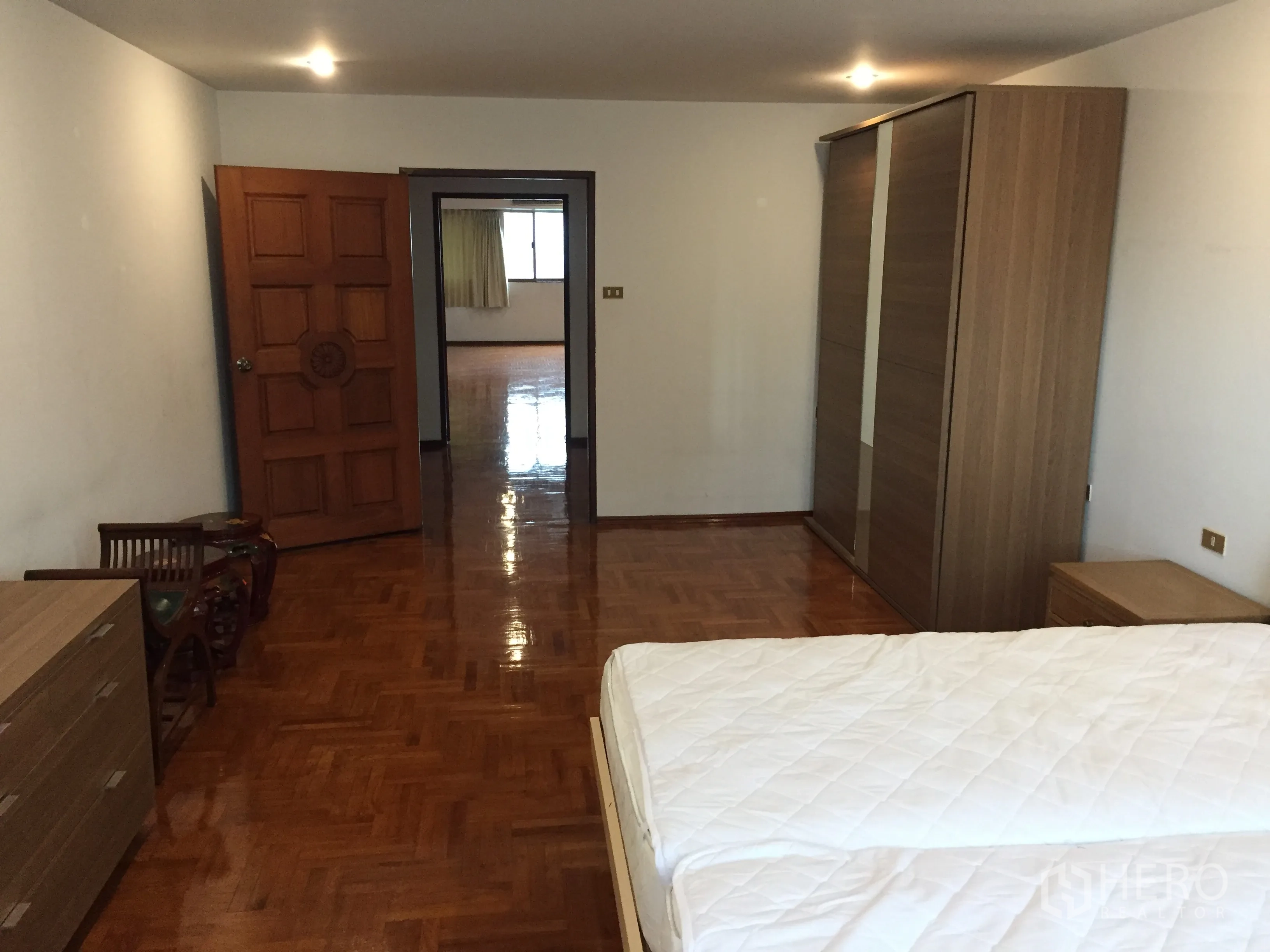 คอนโด ให้เช่าในWatthana, Bangkok - มุมมองจากห้องนอนไปยังพื้นที่นั่งเล่น ตู้เสื้อผ้าบานเลื่อนและพื้นไม้