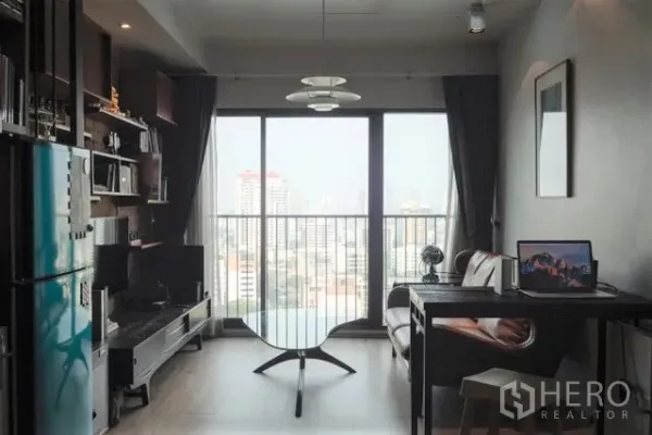 公寓 出租在Khlong Toei, Bangkok - 客厅设大落地窗观景，工作桌、沙发与置物架。