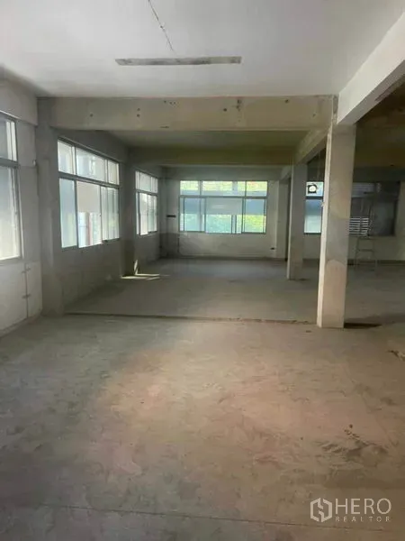 Home Office for rent in Watthana, Bangkok - Open-plan unfinished floor with large windows and concrete columns letting in natural light.