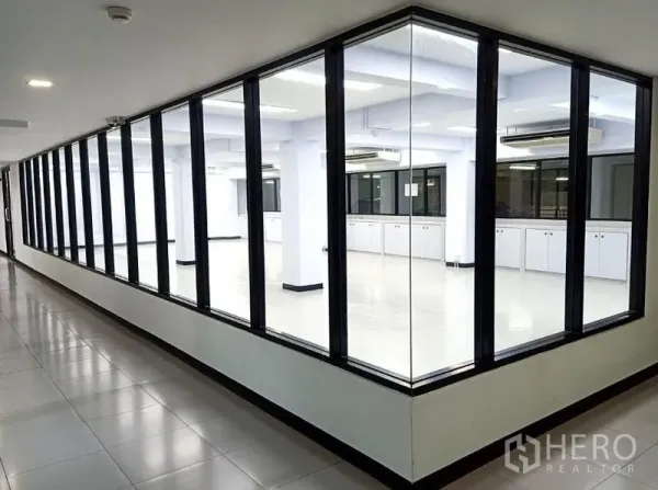 办公空间 出租在Watthana, Bangkok - 走廊视角的玻璃转角办公室，黑框落地玻璃。