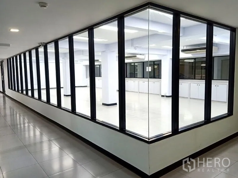 办公空间 出租在Watthana, Bangkok - 走廊视角的玻璃转角办公室，黑框落地玻璃。
