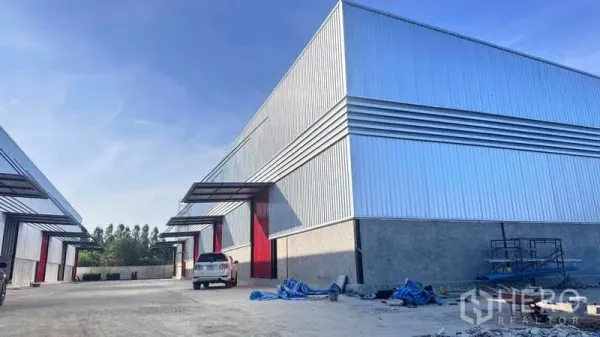 货栈 出租在Khlong Sam Wa, Bangkok - 金属板外墙仓库外观，红色大门，车道与停车区域。