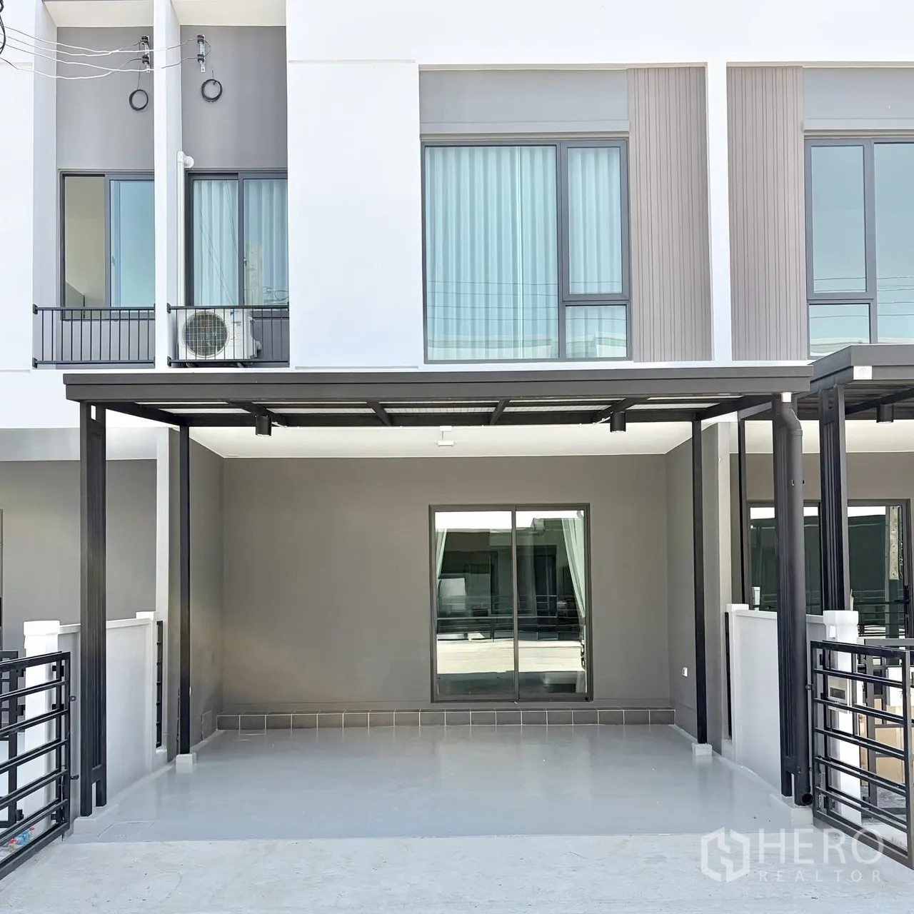 Townhouse for rent in Bang Phli, Samut Prakan - Modern two-storey townhouse facade with a covered two-car carport and sliding glass door.