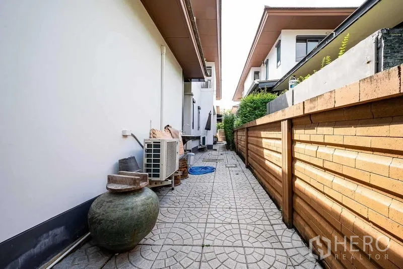Detached House for sale in Prawet, Bangkok - Side walkway of the house with brick fence and outdoor utilities.