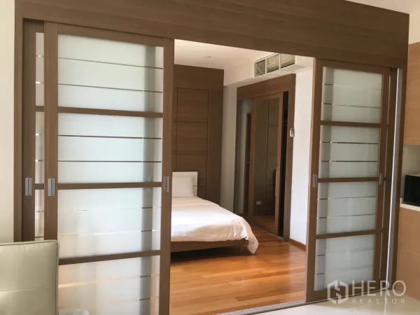 公寓 出租或出售在Khlong Toei, Bangkok - 卧室木地板、镜面衣柜与磨砂玻璃隔断。