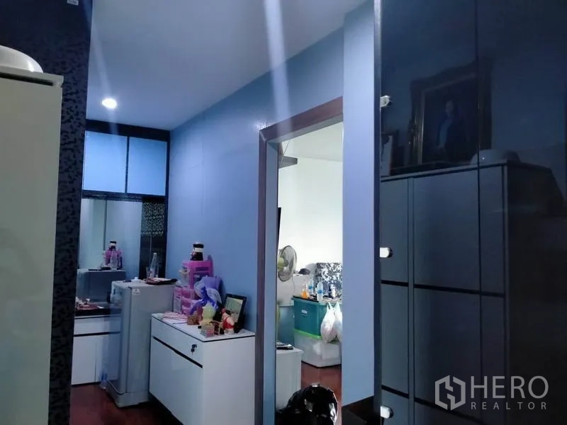 บ้าน ขายในThawi Watthana, Bangkok - โถงทางเดินผนังสีฟ้า ตู้เก็บของ และไฟฝังฝ้า เชื่อมต่อสู่ห้องถัดไป