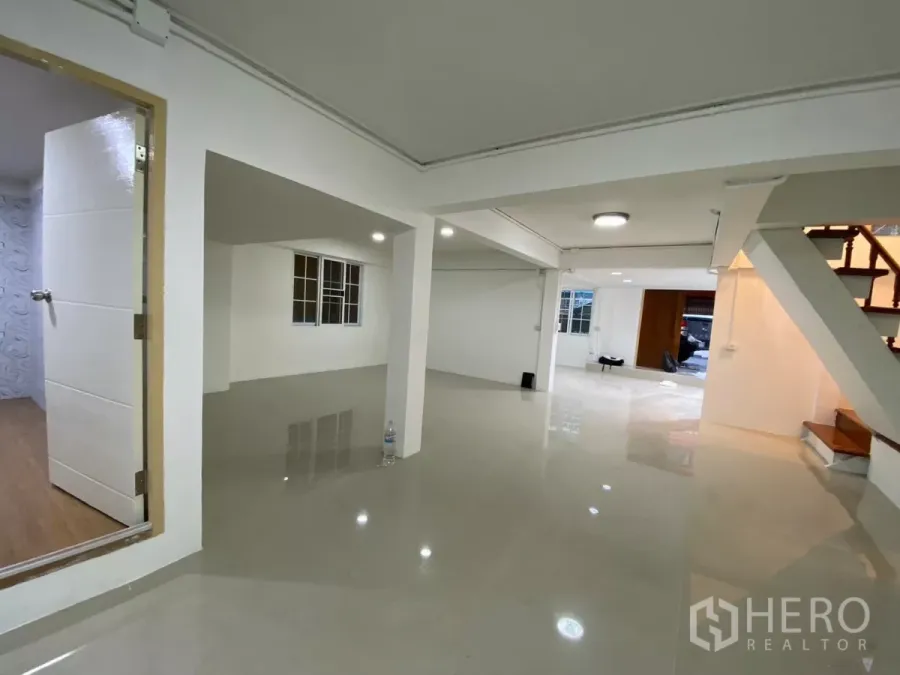 Detached House for rent in Bang Na, Bangkok - Open-plan ground floor living space with glossy tiled floors, windows and a staircase leading upstairs.
