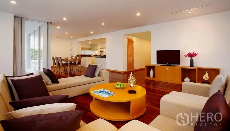 Condominium for rent in Watthana, Bangkok - Spacious living and dining area with sofas, TV console, hardwood floors and sliding doors to a balcony in a condo near BTS Ekkamai.